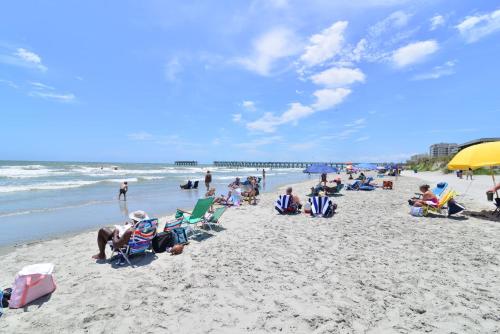 a group of people sitting in chairs on the beach at Captain's Cove - Pool Rooftop and Inlet Views in Myrtle Beach