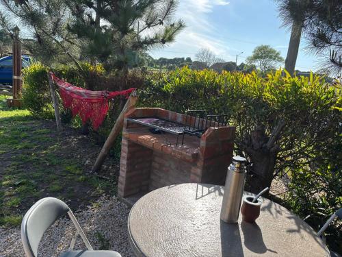 an outdoor table with a brick grill in a yard at Tiny House con parrilla y jardín cerca del mar in Colonia Chapadmalal