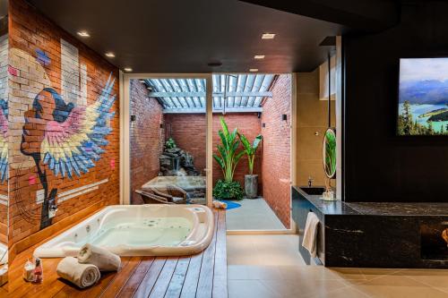ein Badezimmer mit einer Badewanne und einem Gemälde an der Wand in der Unterkunft Monn Cherry Motel in Lajeado