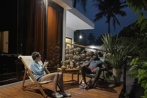 a group of people sitting on a porch at night at CosyBe Villas in Praia do Tofo
