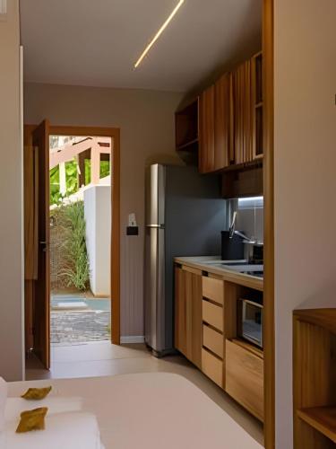 a kitchen with wooden cabinets and a stainless steel refrigerator at MAR DÁ LIBERDADE com Amerigo Vespucci in Morro de São Paulo