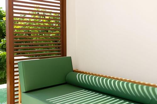 a green bench sitting in front of a window at MAR DÁ LIBERDADE com Amerigo Vespucci in Morro de São Paulo