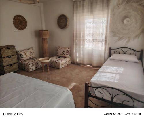 a bedroom with two beds and a chair and a window at Ferme d'hôtes Aghbalou in Sefrou