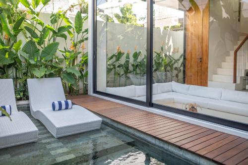 a patio with two white chairs and a couch at Casa Goya Pererenan by REJA Villas in Badung