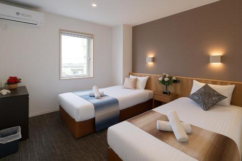 een hotelkamer met twee bedden en een raam bij Plaza In Kanku Hotel in Izumi-Sano