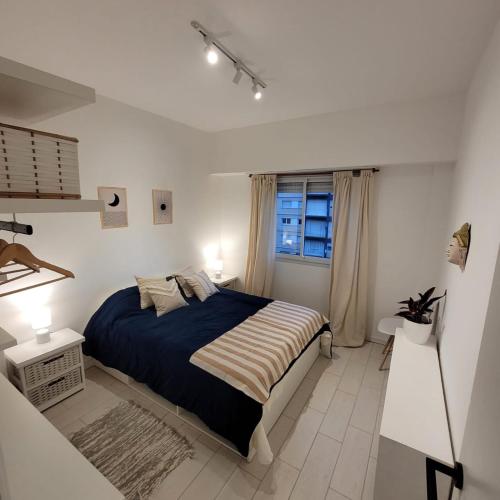 a white bedroom with a bed and a window at Depto 3amb en Torreón del Monje in Mar del Plata