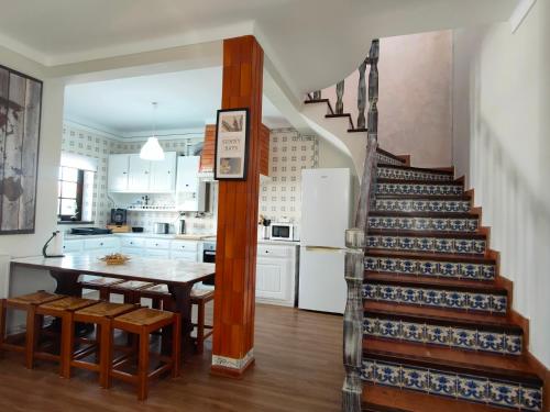 a kitchen and dining room with a staircase and a table at Baleal Classic Waves Guest House in Baleal