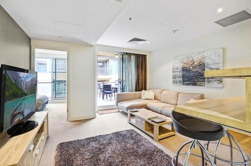 グレネルグにあるSeaside Apartment with Shared Gym & Saunaのソファとテレビのあるリビングルーム