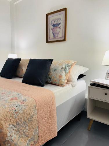 a bedroom with a bed with pillows and a picture on the wall at Loft Santorini II in Manaus