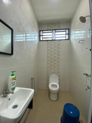 a white bathroom with a sink and a toilet at Teratak Bonda Zariah Homestay in Kota Bharu