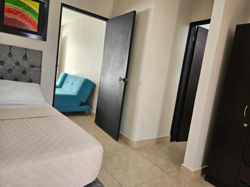 a bedroom with a bed and a blue chair at Caribbean Island Hotel Piso 2 in San Andrés