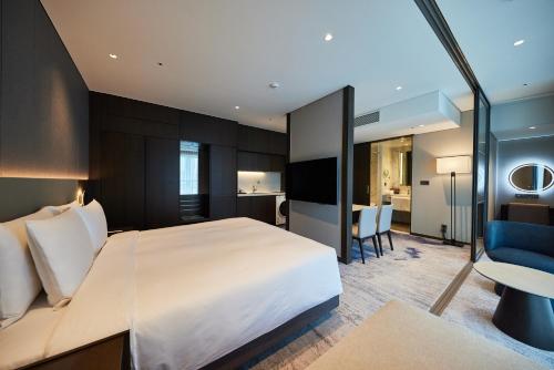 a bedroom with a large white bed and a kitchen at Hotel HLB in Busan