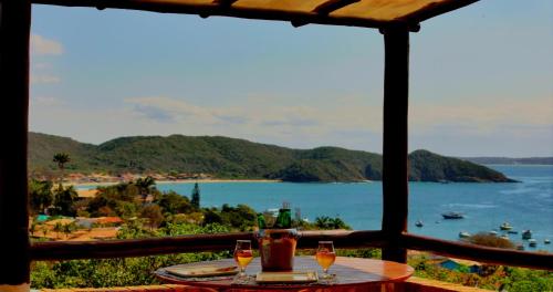 a table with wine glasses and a view of the ocean at Pousada Janellas do Mar in Búzios