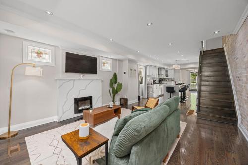 a living room with a green couch and a fireplace at Entire Unit - Steps From History - 5 Mins To Beaches in Toronto