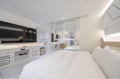 a white bedroom with a large bed and a television at Gimhae Hotel Hiem in Samgong