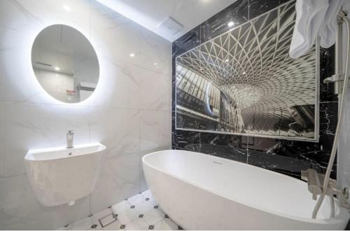 a bathroom with a tub and a sink and a mirror at Gimhae Hotel Hiem in Samgong