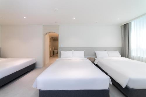two beds in a hotel room with white sheets at Hotel Modak Namdaemun in Seoul