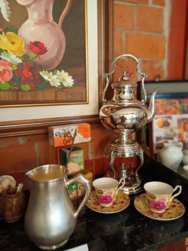 a tea kettle and two cups on a table at Pousada Casa Jardim in Serra Negra