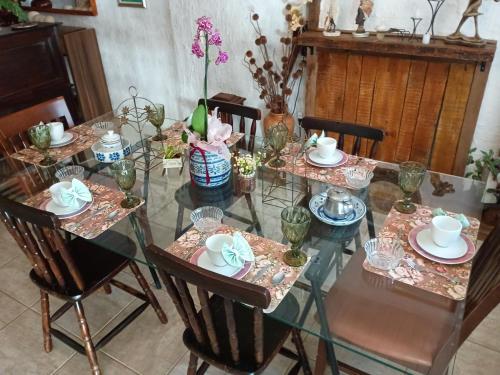 a glass table with chairs and vases on it at Pousada Casa Jardim in Serra Negra