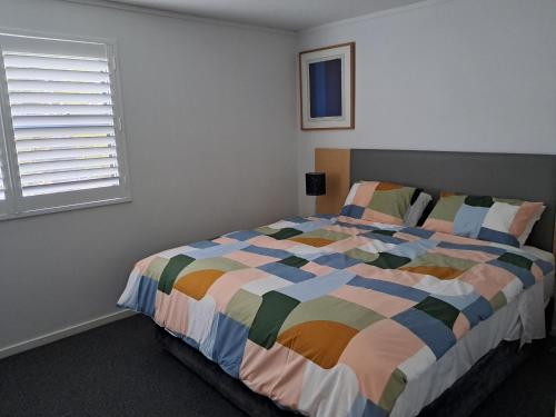 Un dormitorio con una cama colorida con una ventana. en Batehaven Resort, en Batehaven