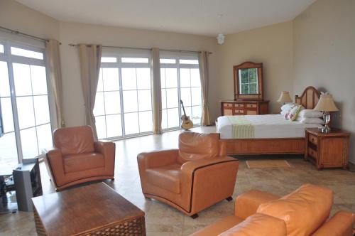 a bedroom with a bed and a couch and chairs at Bord Mer House in Glacis