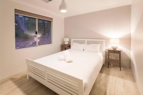 a bedroom with a large white bed and a window at Manyatta Secluded in Nature Close to Attractions in Quindalup