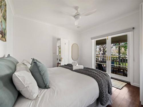 ein weißes Schlafzimmer mit einem Bett und einem Fenster in der Unterkunft Newberry Cottage - Beach, Games & Alfresco Bliss in Dunsborough