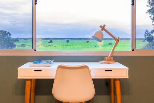 a desk with a lamp and a chair in front of a window at Oasis - Tranquil Getaway with Pool and Scenic Outlooks in Quindalup