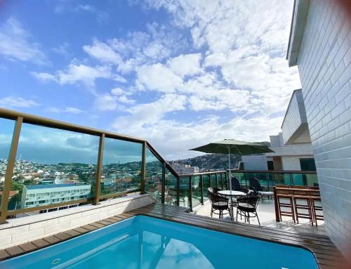 アハイアウ・ド・カボにあるCobertura Pé na Areia- Piscina, Churrasqueira, Vista Mar e a 50m da Praia dos Anjosのバルコニー(プール、テーブル、椅子付)