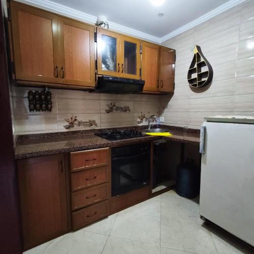a kitchen with wooden cabinets and a white refrigerator at Near everything in m'diq, beach, souk, transport in M'diq