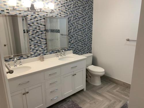 a bathroom with two sinks and a toilet and a mirror at Fully furnished Condo in Deerfield Beach