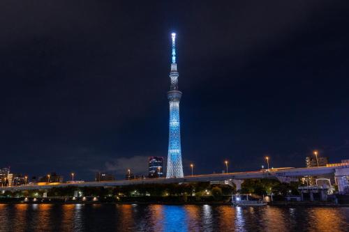 a tall tower lit up in blue at night at Skytree View Rooftop Villa Asakusa SVRVA in Tokyo