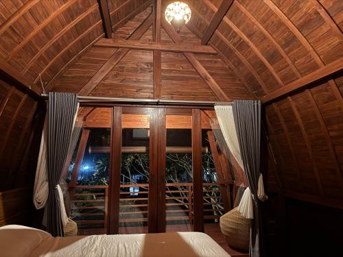 a bedroom with a wooden ceiling with a window at Umah Lumbung Estetik in Tanah Lot