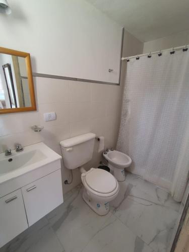 a white bathroom with a toilet and a sink at Tu Lugar en Capilla Del Monte in Capilla del Monte