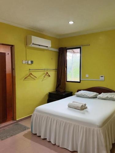 Un dormitorio con una gran cama blanca con paredes amarillas. en Hotel Rembau, en Rembau