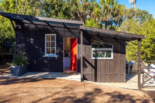 Palm BeachにあるJacksons Hideaway - Stay Waihekeの赤い扉の黒小屋