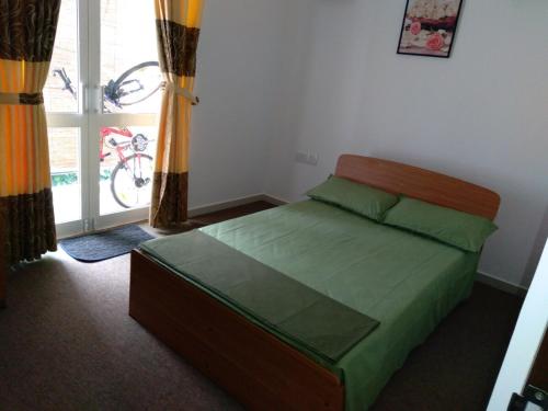 a bedroom with a bed with green sheets and a window at Mystical Rose in Malabe