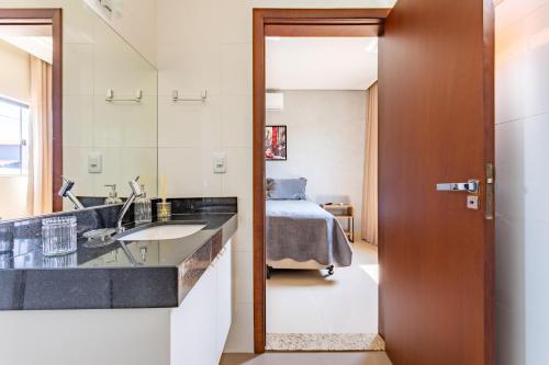 a bathroom with a sink and a bedroom with a bed at Suítes Casa Verde Taquari - 10min da Asa Norte e 5min da Granja do Torto in Brasilia