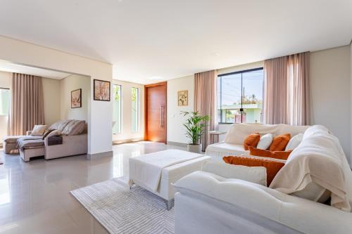 a large living room with white furniture and windows at Suítes Casa Verde Taquari - 10min da Asa Norte e 5min da Granja do Torto in Brasilia