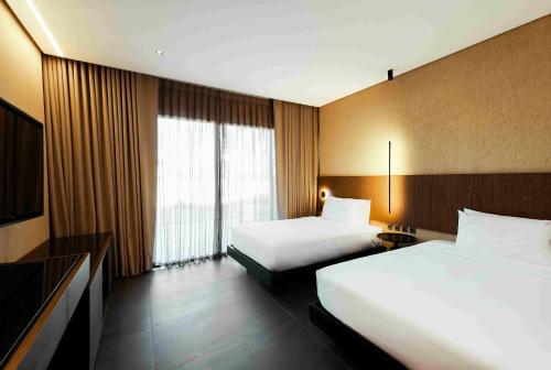 a hotel room with two beds and a television at The Funny Lion - Puerto Princesa in Puerto Princesa City