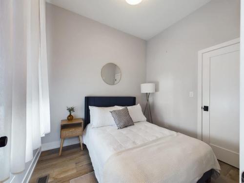 a white bedroom with a bed and a table at West Town 2BR with In-Unit Laundry and Onsite Parking in Chicago