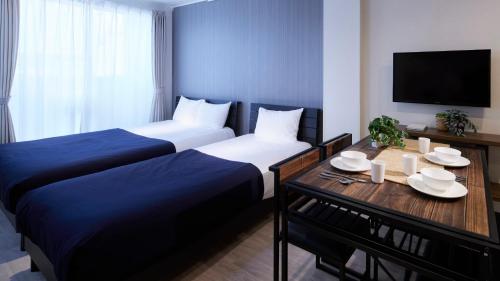 a hotel room with two beds and a table with plates on it at Minn Kamata in Tokyo