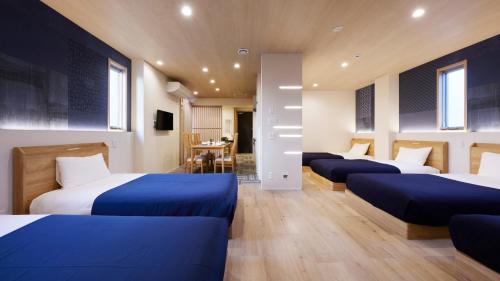 a room with four beds with blue sheets in it at Minn Kamata in Tokyo