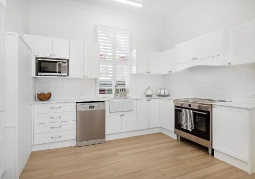 Una cocina con gabinetes blancos y un horno de estufa. en Seabreeze Luxury Beach House Kiama, en Kiama