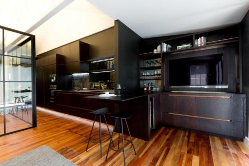 een keuken met zwarte kasten en een bar met krukken bij Moa Studios - Stay Waiheke in Blackpool