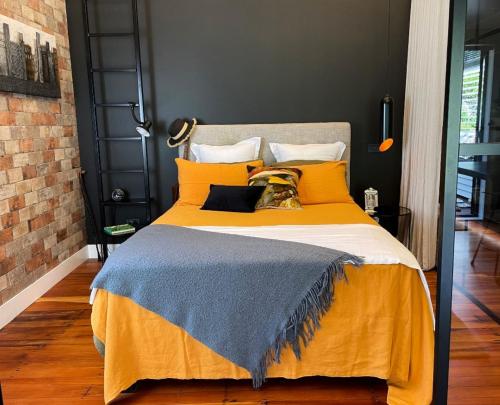 een slaapkamer met een groot bed met gele dekens en kussens bij Moa Studios - Stay Waiheke in Blackpool