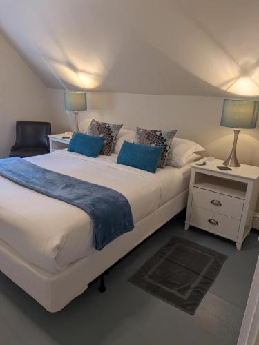 a bedroom with a large white bed with blue pillows at The Maisonette by Corbitt Hospitality in Annapolis Royal