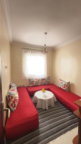 a living room with a red couch and a table at Cozy Apartment Near Rabat & Beach in Temara