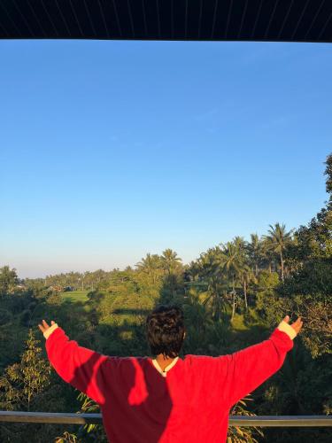 a man with his arms outstretched looking out over a forest at Lalinggo Bungalow in Tetebatu