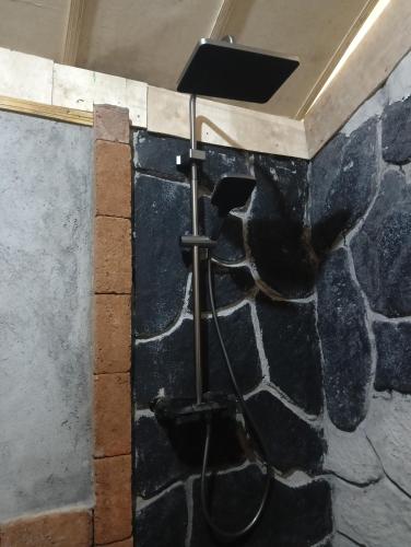 a shower in a room with a stone wall at Lalinggo Bungalow in Tetebatu